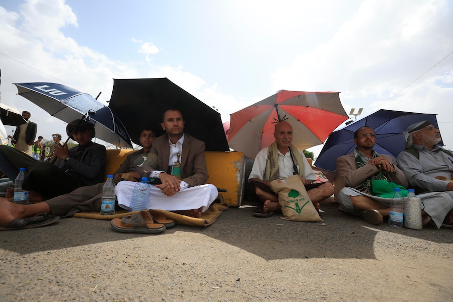 I sostenitori degli Houthi si riparano dal sole sotto gli ombrelli durante una manifestazione contro l’Arabia Saudita, a Sana’a, nello Yemen. (EPA/Yahya Arhab)