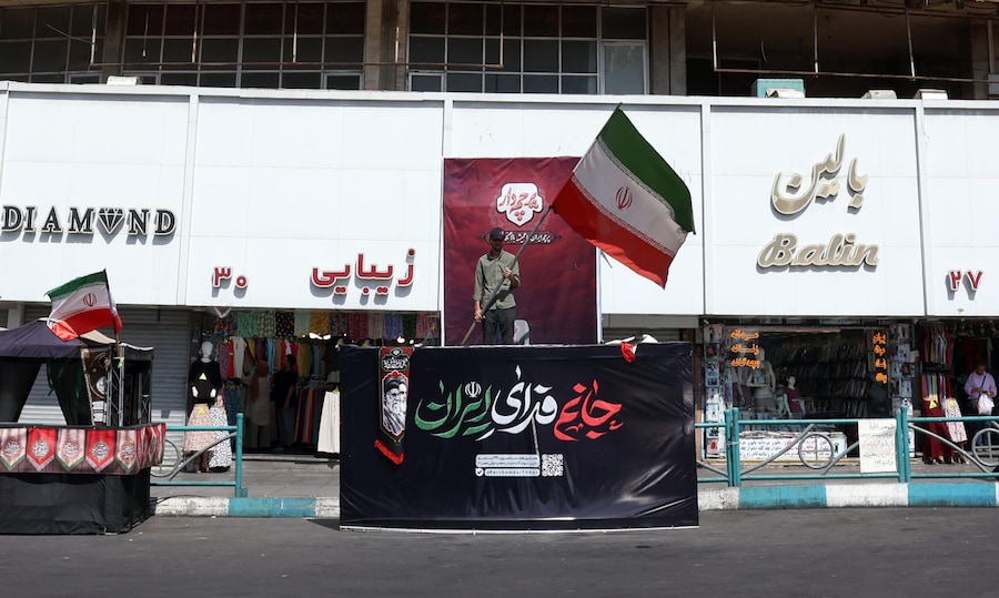 Un uomo iraniano tiene in mano la bandiera nazionale iraniana davanti a un grande cartellone politico in piazza Valiasr a Teheran, in Iran. Le tensioni tra l’Iran e gli Stati Uniti riguardo allo Stretto di Hormuz continuano dopo che il presidente degli Stati Uniti Donald Trump ha segnalato la possibilità di ulteriori attacchi statunitensi contro l’Iran. (EPA/Abedin Taherkenareh)