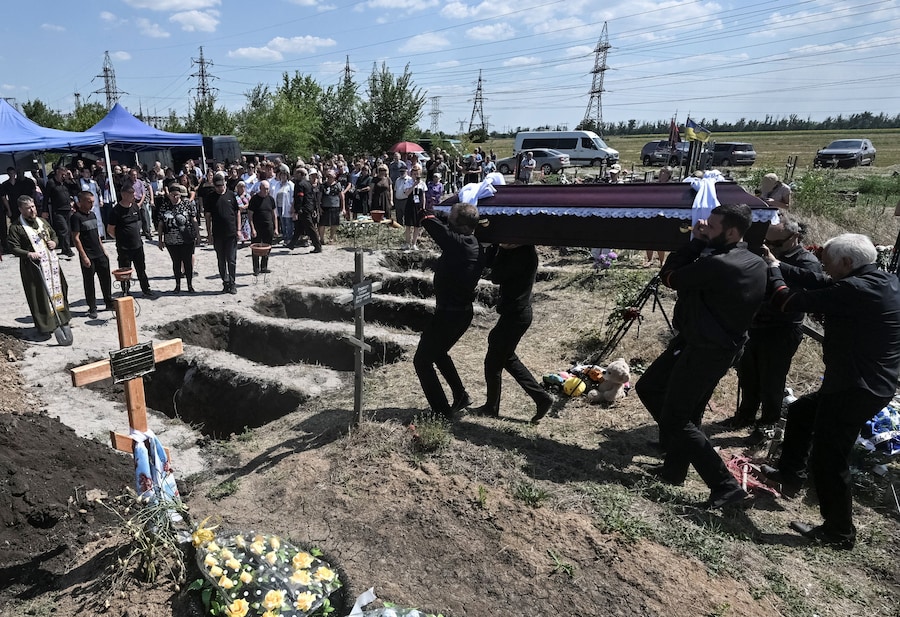 La gente partecipa alla cerimonia funebre della famiglia Voronov, rimasta uccisa durante un attacco missilistico russo il 30 luglio, nel contesto dell’offensiva russa contro l’Ucraina, nel villaggio di Radushne vicino alla città di Kryvyi Rih, nella regione di Dnipropetrovsk. (REUTERS)