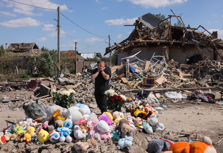 Una persona in lutto piange accanto ai fiori e ai peluche deposti sul luogo dove sorgeva l’ex abitazione della famiglia Voronov, colpita da un missile balistico russo nel villaggio di Radushne, alla periferia di Kryvyi Rih, nella regione di Dnipropetrovsk. (EPA)