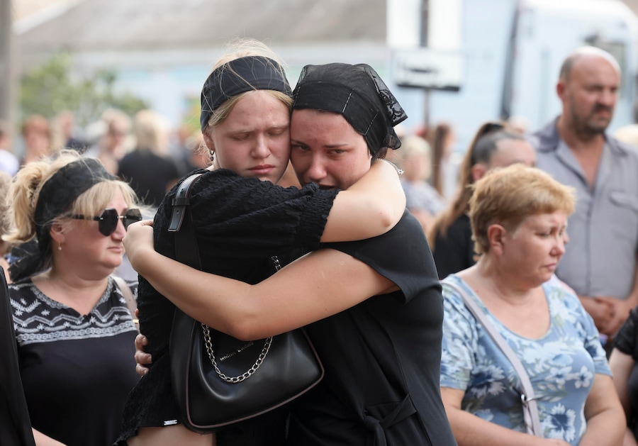 I partecipanti al funerale reagiscono mentre assistono alle esequie dei membri della famiglia Voronov, uccisi da un attacco missilistico balistico russo contro la loro abitazione nel villaggio di Radushne, alla periferia di Kryvyi Rih, nella regione di Dnipropetrovsk. (EPA)