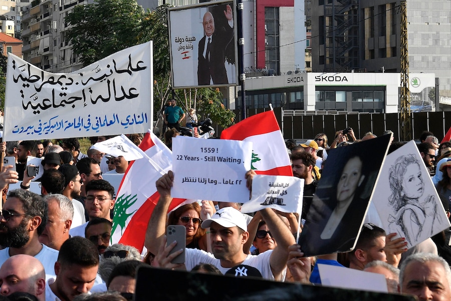 La gente tiene in mano cartelli e bandiere libanesi durante una manifestazione per commemorare le vittime dell’esplosione del porto di Beirut del 2020, a Beirut, in Libano. Il Libano commemora i sei anni dall’esplosione che il 4 agosto 2020 ha devastato l’area portuale di Beirut, causando la morte di almeno 200 persone e il ferimento di altre migliaia. Si ritiene che l’esplosione sia stata causata dall’accensione di circa 2.750 tonnellate di nitrato di ammonio stoccate in un magazzino del porto. (EPA/Abbas Salman)