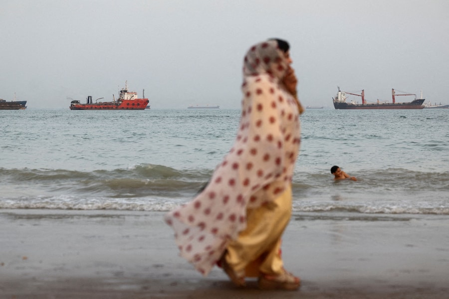 Persone che passeggiano sulla spiaggia, con imbarcazioni nello Stretto di Ormuz visibili nei pressi della spiaggia di Bandar Abbas, in Iran. (Majid Asgaripour/WANA (West Asia News Agency) via REUTERS)