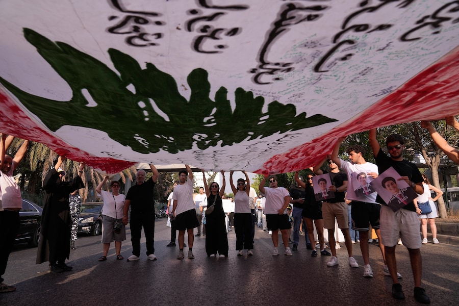 I parenti delle vittime dell’esplosione del porto di Beirut del 2020 sventolano una gigantesca bandiera libanese e mostrano i ritratti dei propri cari mentre sfilano durante una cerimonia commemorativa per il sesto anniversario della violenta esplosione avvenuta a Beirut, in Libano. (AP Photo/Hussein Malla/Associated Press / LaPresse/APN)