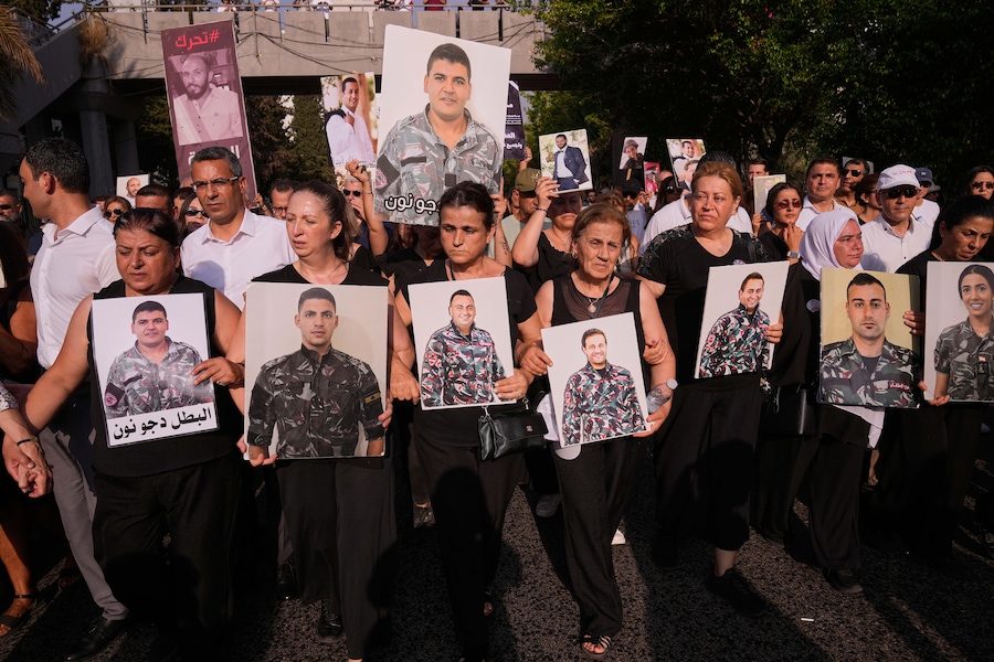 I familiari dei vigili del fuoco rimasti uccisi nell’esplosione del porto di Beirut del 2020 tengono in mano le loro foto mentre sfilano durante una cerimonia commemorativa in occasione del sesto anniversario della violenta esplosione avvenuta a Beirut, in Libano. (AP Photo/Hussein Malla/Associated Press / LaPresse/APN)