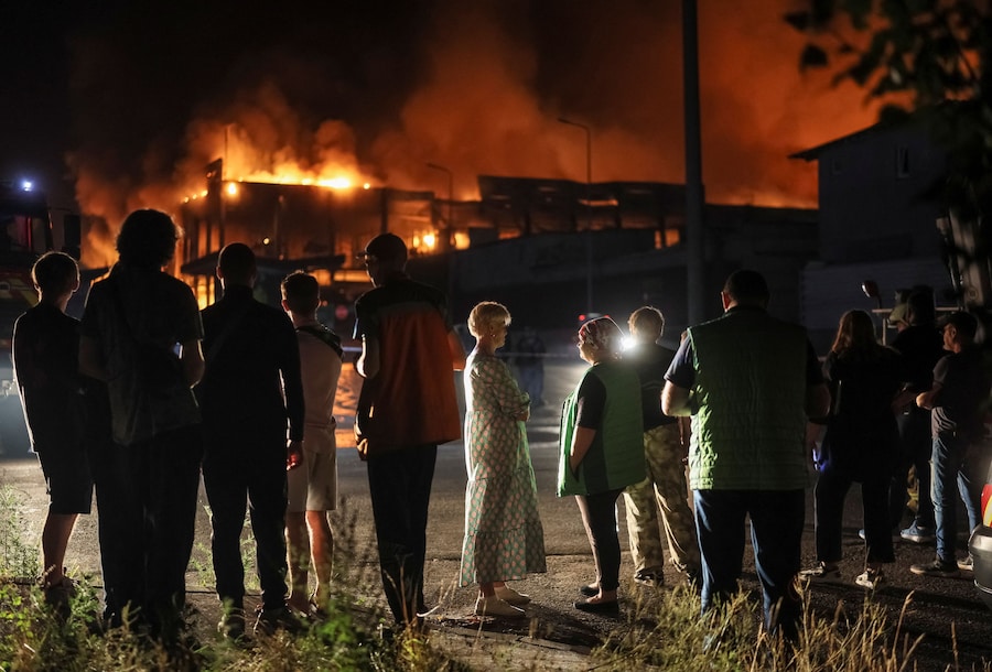 Alcuni residenti si trovano sul luogo in cui sorge il magazzino di un supermercato colpito da un missile russo, a Kiev, Ucraina, il 5 agosto 2026. (REUTERS/Gleb Garanich)