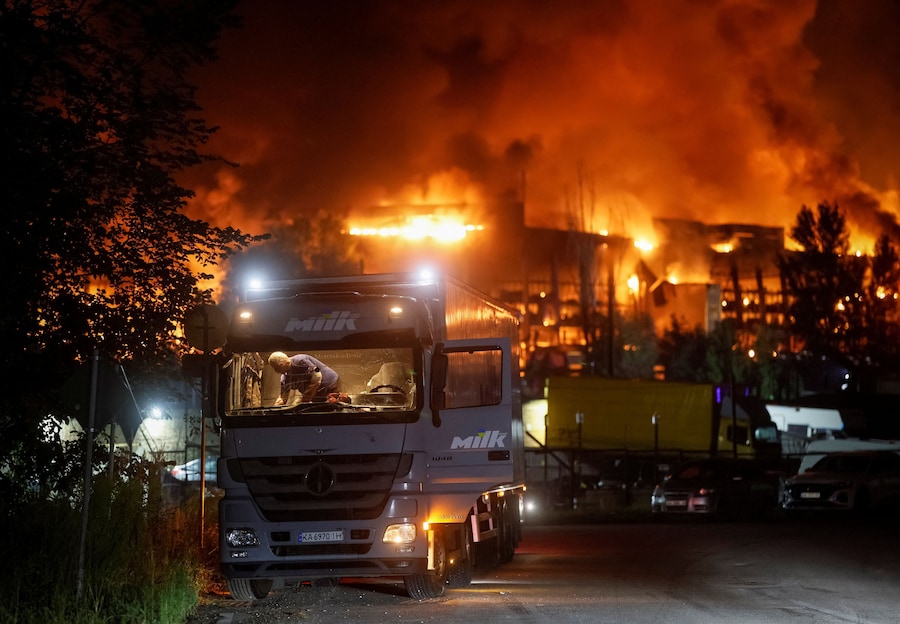 Un autista ferito pulisce i frammenti di vetro dall'abitacolo di un camion danneggiato sul luogo della costruzione di un magazzino di un supermercato colpito da un attacco missilistico russo, a Kiev, Ucraina, il 5 agosto 2026. (REUTERS/Gleb Garanich)