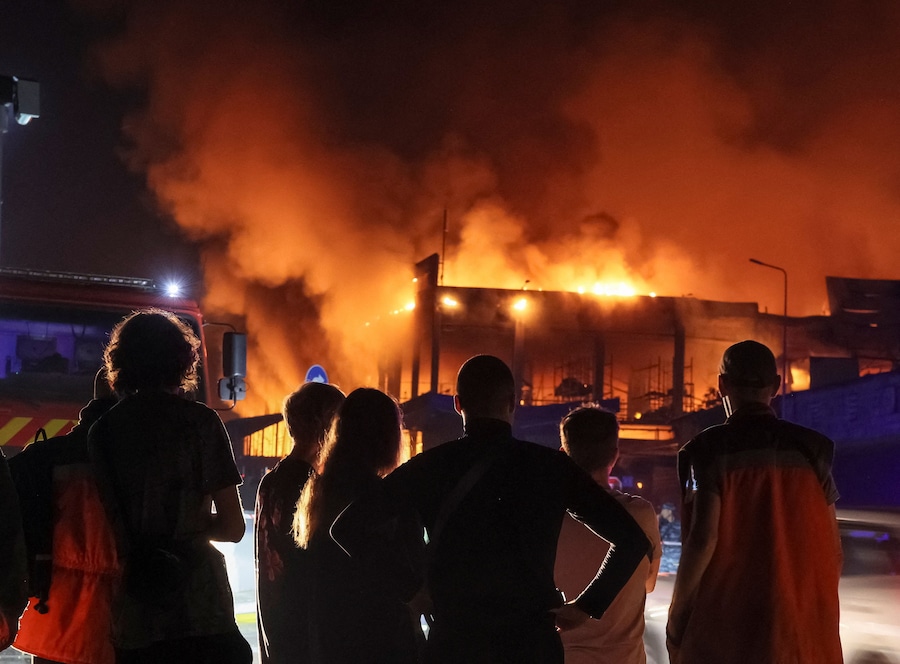 Alcuni residenti si trovano sul luogo in cui sorge il magazzino di un supermercato colpito da un missile russo, a Kiev, Ucraina, il 5 agosto 2026. (REUTERS/Gleb Garanich)