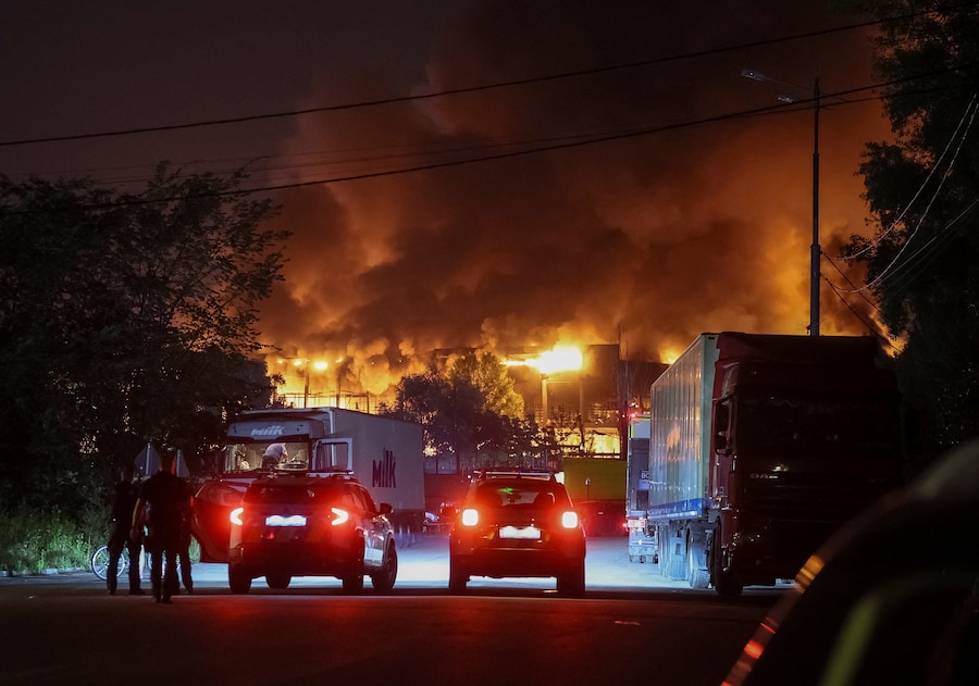 Un agente di polizia sorveglia l'edificio di un magazzino di un supermercato in fiamme a seguito di un attacco missilistico russo, a Kiev, Ucraina, il 5 agosto 2026. (REUTERS/Gleb Garanich)