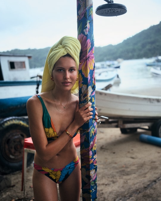 Bikini in jersey elasticizzato stampato (600 €), asciugamano in spugna di cotone (270 €), orecchini in metallo e pelle (590 €) e bracciale in smalto e metallo placcato oro (660 €), tutto HERMÈS.