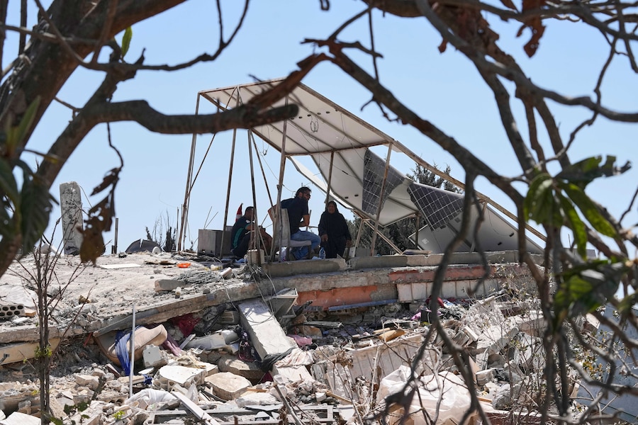 Una famiglia libanese si ripara all'ombra dei pannelli solari danneggiati della propria casa distrutta nel villaggio di Zawtar al-Gharbieh, nel sud del Libano. (APN)