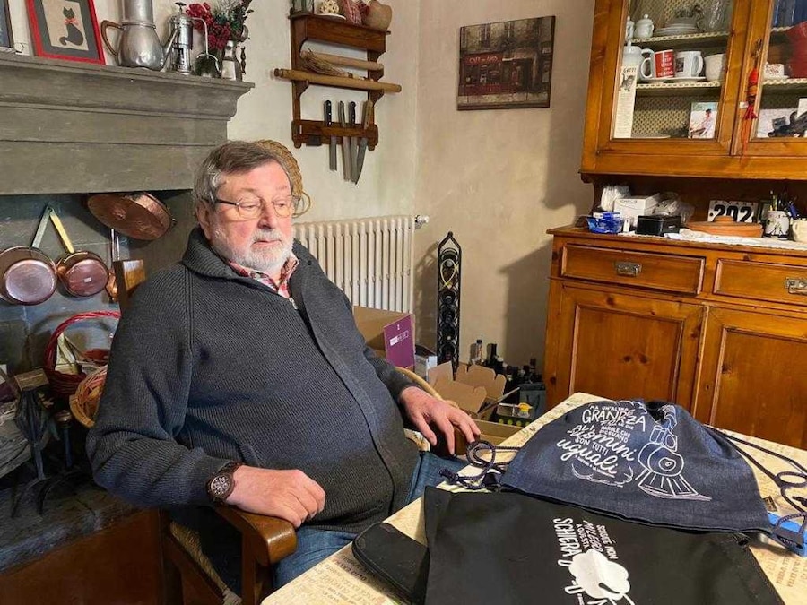 Francesco Guccini ritratto con gli zaini con i versi delle sue canzoni confezionati dalla sartoria all'interno della Casa circondariale di Bologna, in una foto diffusa il 18 ottobre 2021. (ANSA/ Siamo qua Società Cooperativa Onlus)