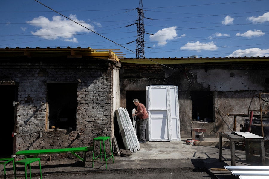 Un uomo trasporta delle porte all’interno della struttura di un impianto di lavorazione dei prodotti ittici che è andata in fiamme durante un recente attacco russo, nel contesto dell’offensiva russa contro l’Ucraina, a Zaporizhzhia. (REUTERS)