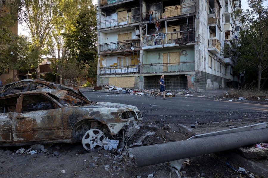 Un uomo passa accanto ad auto bruciate e a un edificio residenziale che è andato a fuoco durante un recente attacco russo, sparsi in una zona residenziale, nel contesto dell'offensiva russa contro l'Ucraina, a Zaporizhzhia. (REUTERS)