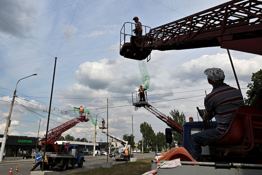 Operai installano reti anti-drone sopra una strada, mentre la Russia attacca l’Ucraina, in un quartiere a sud di Zaporizhzhia. (REUTERS)
