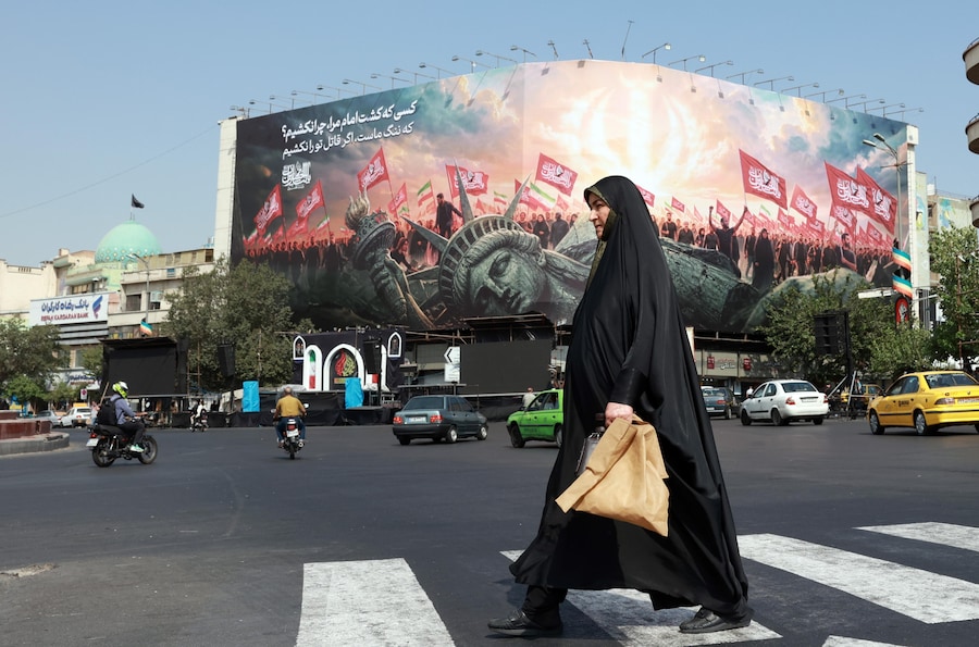 Una donna iraniana con il velo cammina davanti a un cartellone anti-USA in Piazza Enghelab, nel centro di Teheran (Iran) (EPA)