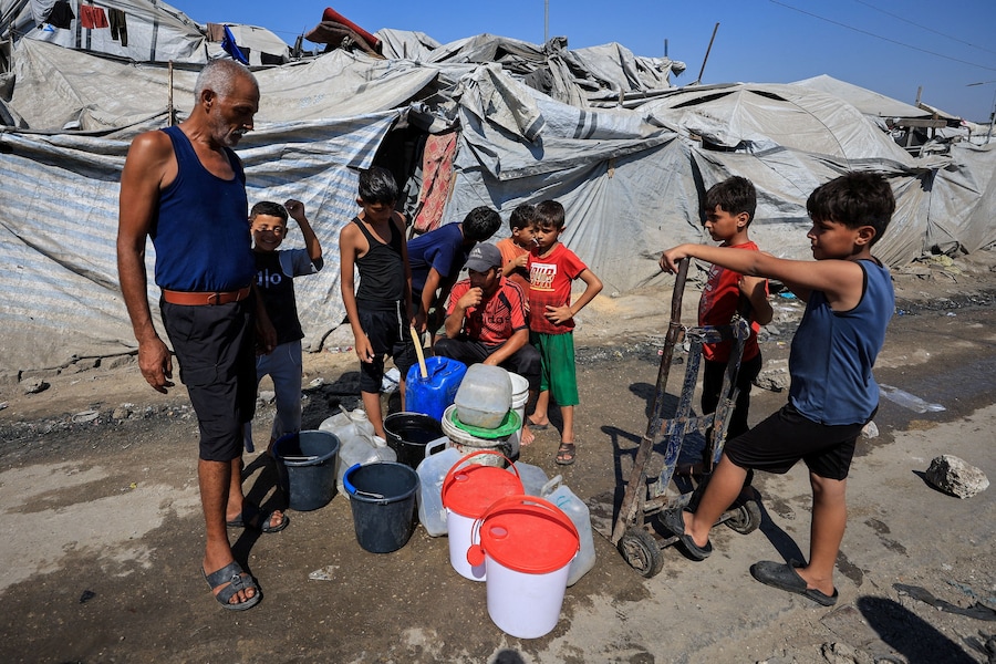 Palestinesi sfollati si radunano per raccogliere acqua in un campo di tende a Gaza City (REUTERS)