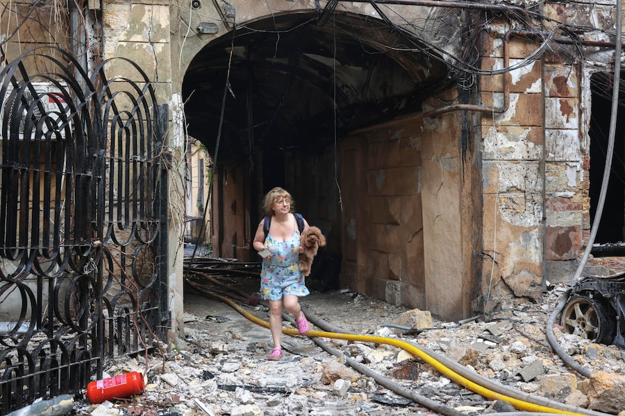 Una donna porta in braccio il proprio cane sul luogo di un attacco russo contro una zona residenziale nel centro di Odessa, in Ucraina, il 9 agosto 2026, nel corso dell’invasione russa. Secondo l’amministrazione militare regionale di Odessa, almeno nove persone sono rimaste ferite in seguito a un attacco russo sferrato durante la notte contro la città. EPA/IGOR MASLOV (EPA)
