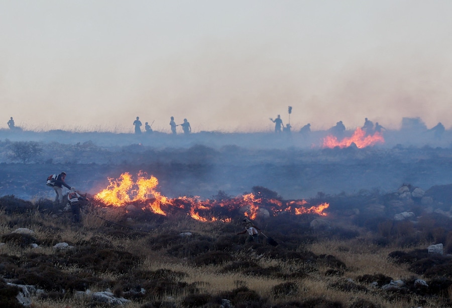 Coloni israeliani spengono un incendio divampato nei pressi di un avamposto di insediamento, vicino alla città palestinese di Taybeh, nella Cisgiordania occupata da Israele (REUTERS)