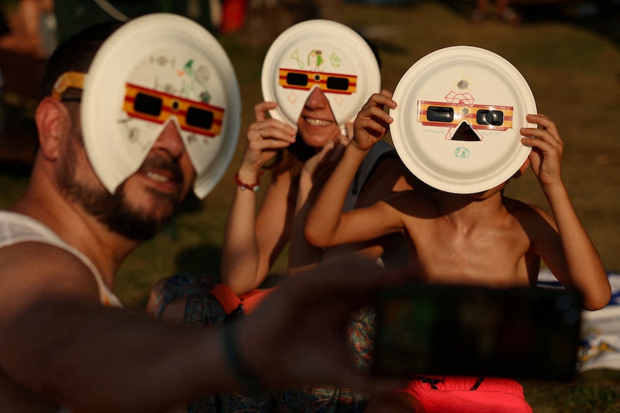 Angela, David e il loro figlio Diego, di 7 anni, posano per un selfie indossando occhiali protettivi per l'eclissi durante la festa organizzata per osservare l'eclissi solare a Buitrago del Lozoya, in Spagna, il 12 agosto 2026. (REUTERS/Susana Vera)