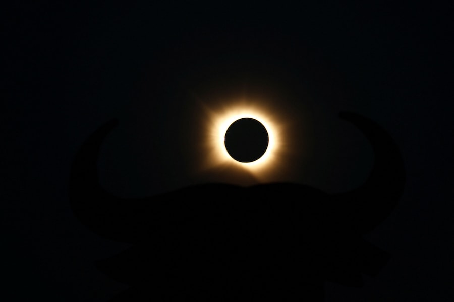 La luna copre completamente il sole durante un'eclissi solare, con sullo sfondo la sagoma di un toro di Osborne, a Navarrete, nel nord della Spagna, il 12 agosto 2026. (REUTERS/Vincent West)