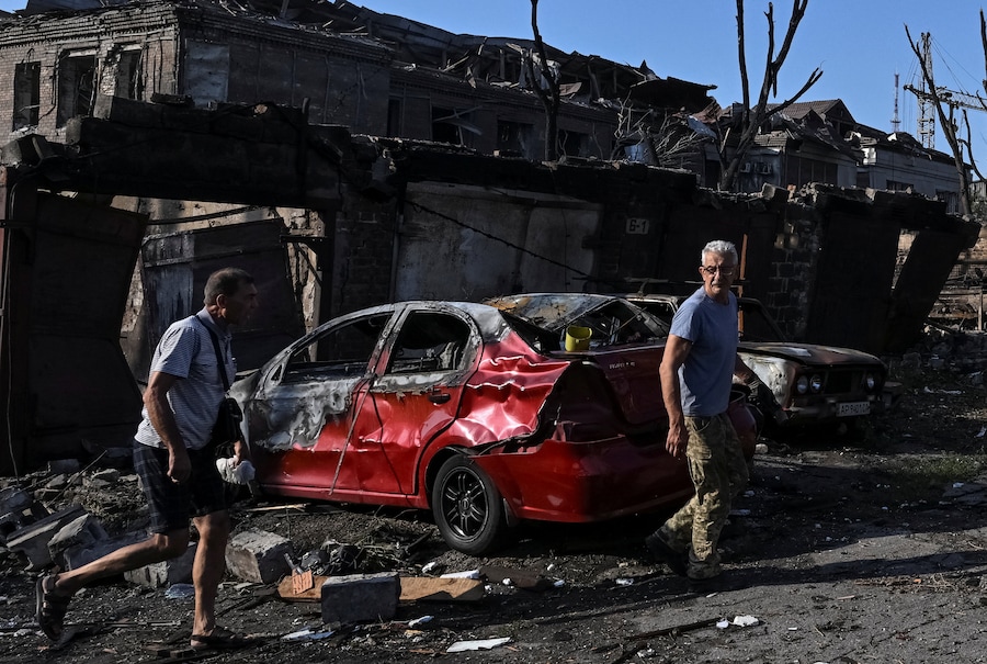 Alcuni residenti camminano sul luogo colpito da un missile e da un attacco aereo russi a Zaporizhzhia, Ucraina (REUTERS)