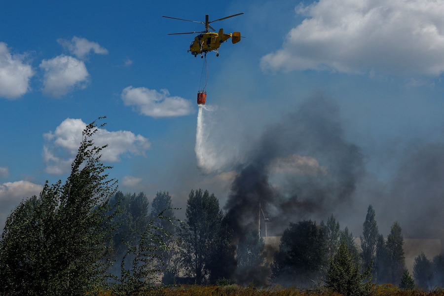 Un elicottero antincendio scarica acqua su un magazzino alimentare danneggiato durante gli attacchi con droni russi nella regione di Kiev (REUTERS)