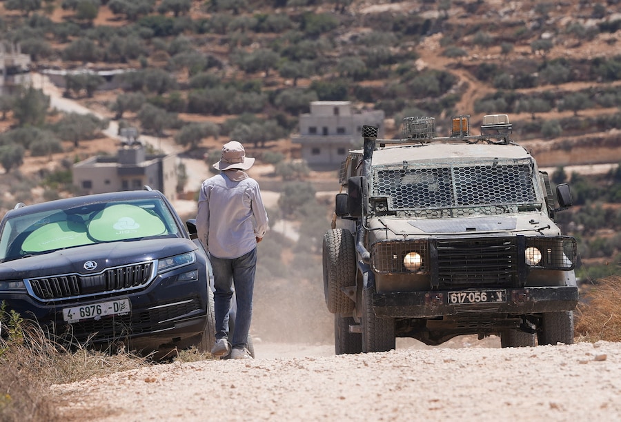 Un veicolo dell'esercito israeliano è fermo nei pressi di un'abitazione palestinese assediata dai coloni israeliani nel villaggio di Qusra, nella Cisgiordania occupata da Israele, il 13 agosto 2026. REUTERS/Ali Sawafta (REUTERS)