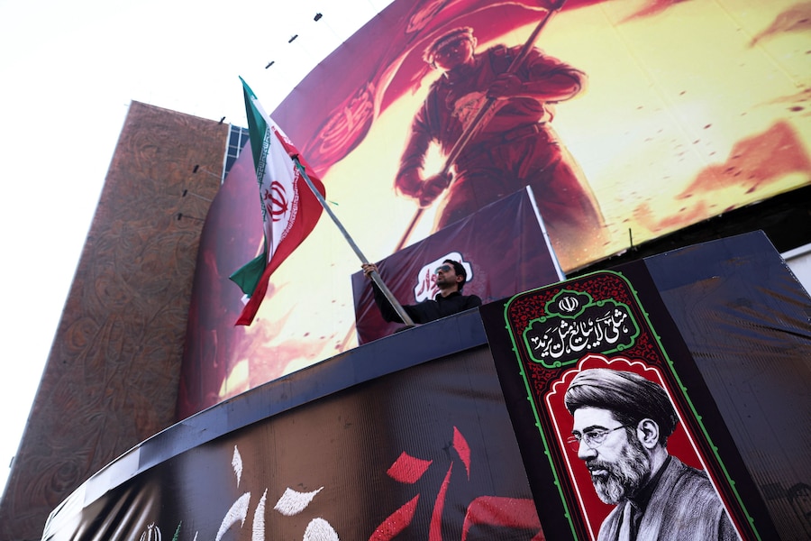 Un uomo tiene in mano una bandiera iraniana, accanto a una foto della Guida Suprema dell'Iran Mojtaba Khamenei, a Teheran, in Iran, il 13 agosto 2026. Majid Asgaripour/WANA (West Asia News Agency) via REUTERS (via REUTERS)