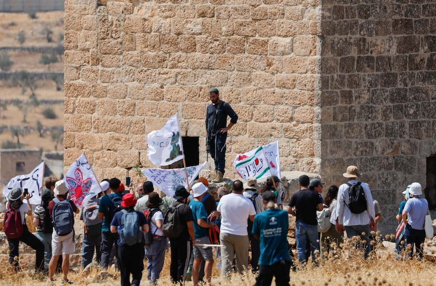 Un colono israeliano armato osserva alcuni attivisti palestinesi e israeliani che accompagnano i proprietari terrieri palestinesi nella loro proprietà, minacciata di confisca da parte dei coloni israeliani, a Beit Sahour, nella Cisgiordania occupata da Israele. (REUTERS)