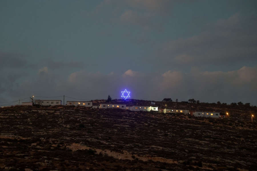 Una Stella di David illuminata sopra un avamposto dei coloni israeliani nei pressi di Ramallah, nella Cisgiordania occupata da Israele, 14 agosto 2026. (REUTERS)