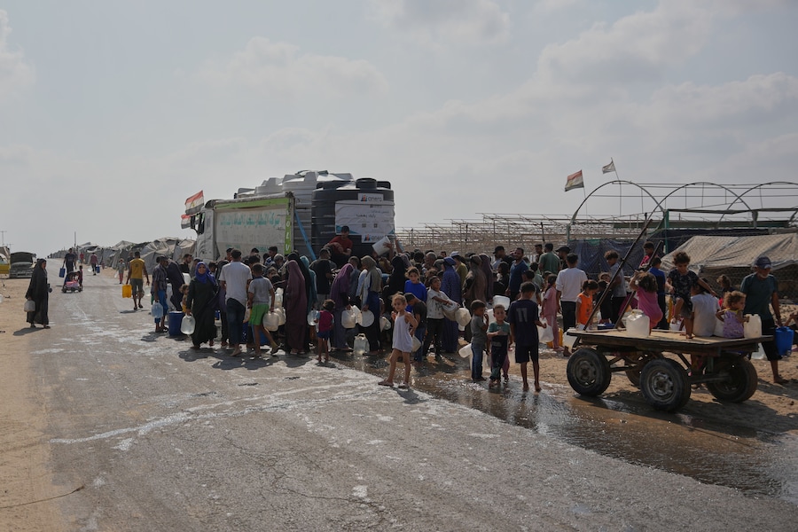 Venerdì 14 agosto 2026, alcuni palestinesi sfollati si radunano presso un punto di rifornimento idrico a Deir al-Balah, nella Striscia di Gaza centrale, per rifornirsi di acqua potabile. (APN)