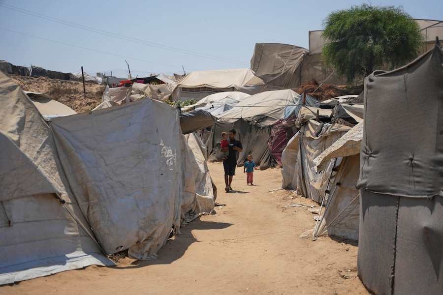 Un uomo palestinese sfollato cammina con i suoi figli in un campo profughi a Deir al-Balah, nella Striscia di Gaza centrale, venerdì 14 agosto 2026. (APN)