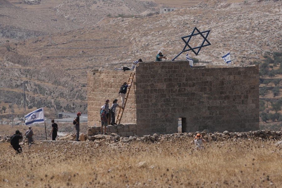 Attivisti per la pace israeliani e stranieri smantellano una struttura metallica a forma di Stella di David dalla sommità di un edificio palestinese durante una manifestazione a sostegno dei proprietari terrieri locali, le cui proprietà rischiano di essere confiscate dai coloni israeliani, alla periferia della città di Beit Sahour, in Cisgiordania, venerdì 14 agosto 2026. (APN)