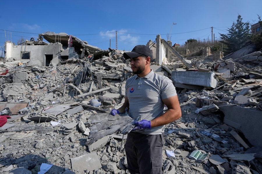Un soccorritore tiene in mano un frammento di scheggia, tra le macerie di un’abitazione distrutta, colpita da un attacco aereo israeliano nel villaggio di Ansar, nel sud del Libano, sabato 15 agosto 2026. (APN)