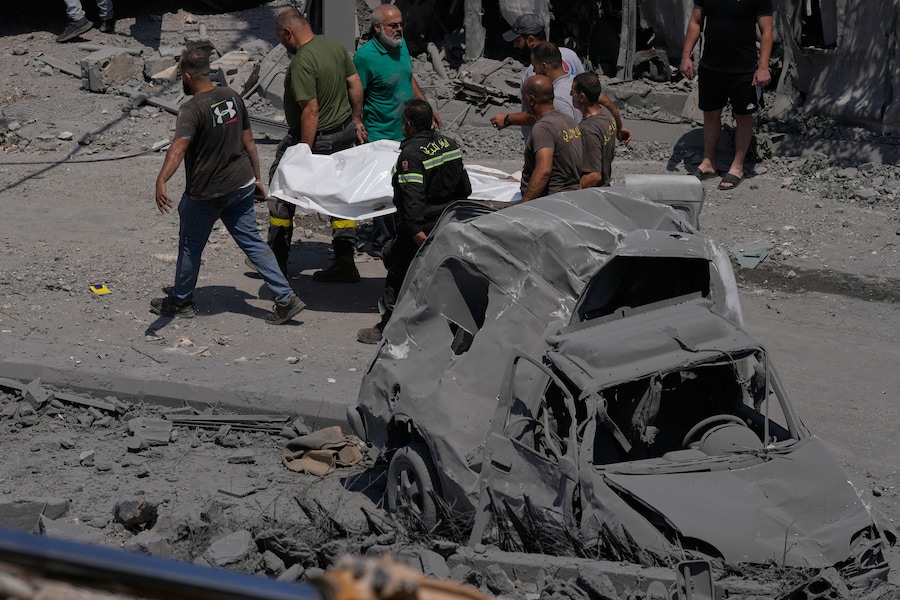I soccorritori trasportano un sacchetto di plastica contenente il corpo di una persona rimasta uccisa in un'abitazione colpita da un attacco aereo israeliano nel villaggio di Deir al-Zahrani, nel Libano meridionale, sabato 15 agosto 2026. (APN)