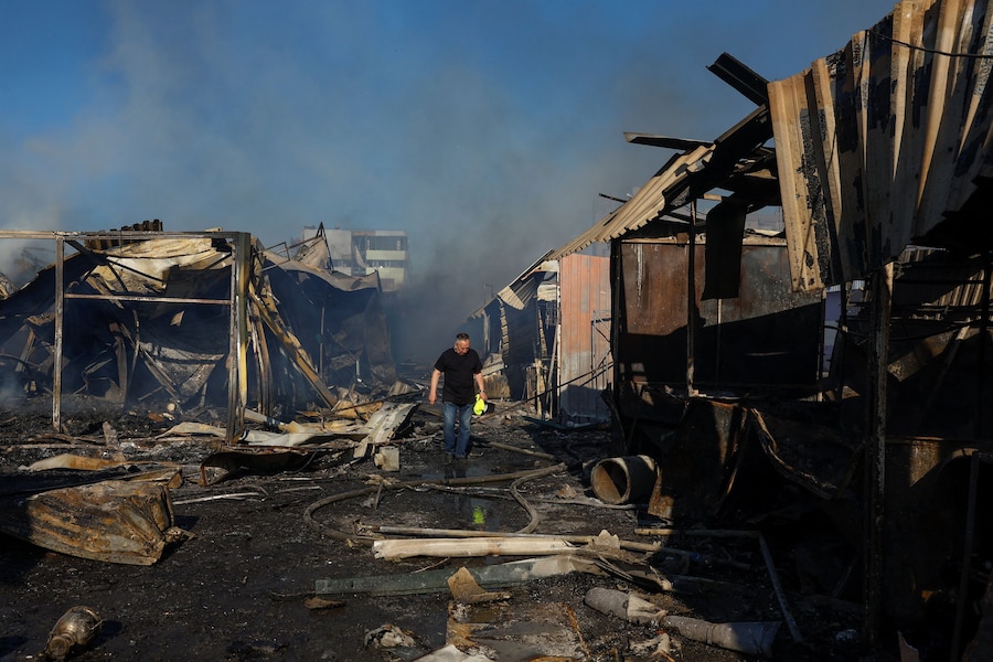 Un residente cammina lungo le file di negozi bruciati nel luogo in cui si trovava un mercato del libro colpito da un attacco missilistico russo, n a Kiev, Ucraina, il 16 agosto 2026. (REUTERS)
