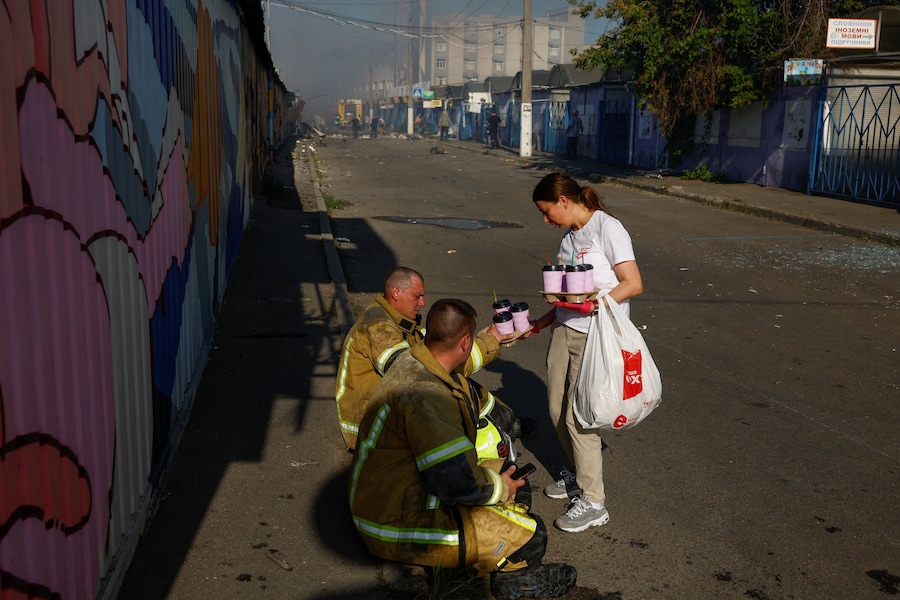 Un residente offre caffè gratuiti ai vigili del fuoco che hanno prestato soccorso sul luogo di un mercatino del libro colpito da un missile russo a Kiev, Ucraina, il 16 agosto 2026. (REUTERS)