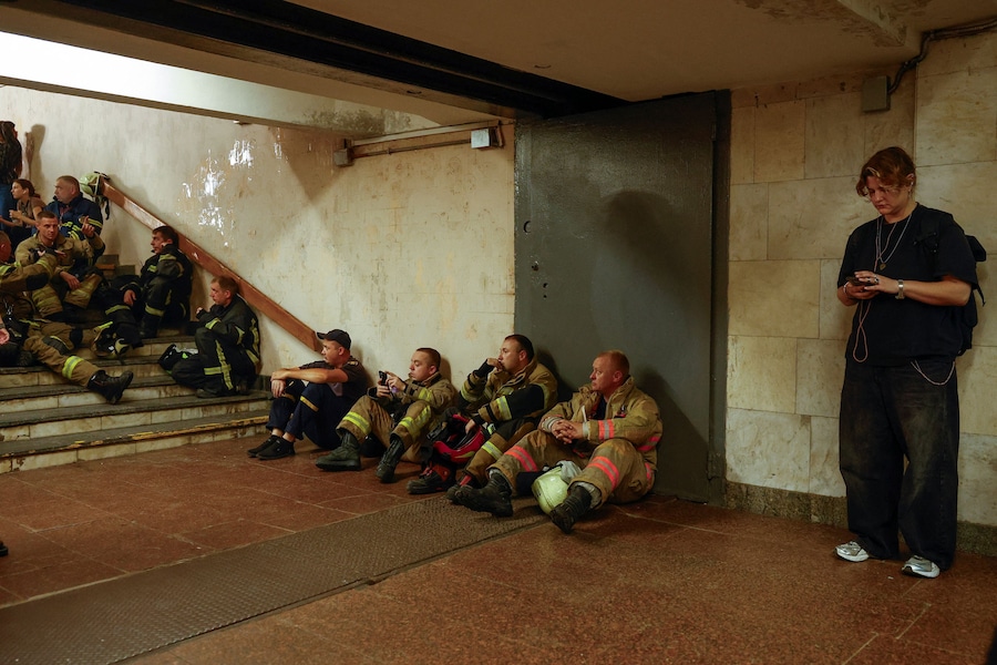 Vigili del fuoco si rifugiano all’interno di un passaggio sotterraneo per proteggersi dal rischio di attacchi di droni mentre lavorano sul luogo di un mercato del libro colpito da un missile russo a Kiev, Ucraina. (REUTERS)