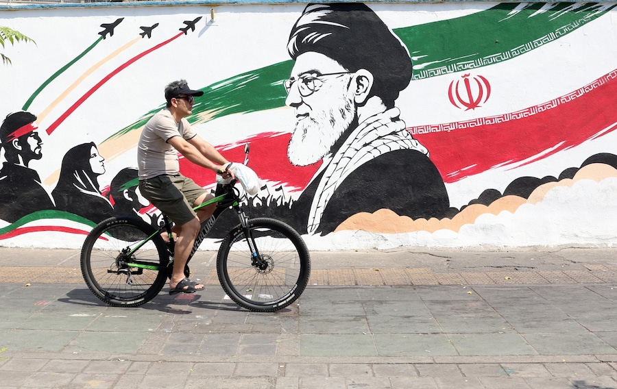 Un uomo iraniano passa in bicicletta accanto a un murale raffigurante il defunto leader supremo iraniano, l’ayatollah Ali Khamenei, in una strada del centro di Teheran, in Iran. Le tensioni tra l’Iran e gli Stati Uniti rimangono elevate, poiché persistono le rivendicazioni contrapposte sul controllo del traffico marittimo nello Stretto di Ormuz. (EPA/Abedin Taherkenareh)
