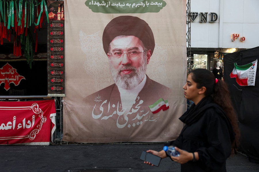 Una donna cammina accanto a uno striscione con l'immagine della Guida Suprema dell'Iran Mojtaba Khamenei, in una strada di Teheran, in Iran. (Majid Asgaripour/WANA (West Asia News Agency) via REUTERS)