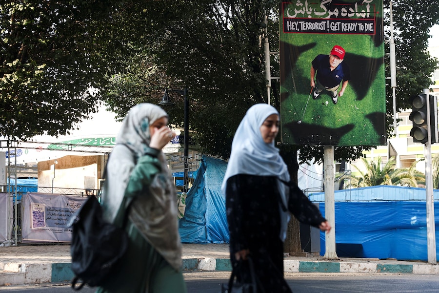 Alcune persone camminano vicino a uno striscione che raffigura il presidente degli Stati Uniti Donald Trump mentre gioca a golf, in una strada di Teheran, in Iran. (Majid Asgaripour/WANA (West Asia News Agency) via REUTERS)