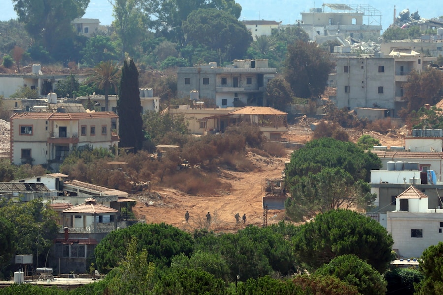 Soldati israeliani camminano nel villaggio di Zawtar al-Sharqiyah, visto da Zawtar al-Gharbiya, nel sud del Libano. Zawtar al-Gharbiya è una delle zone pilota designate nell’ambito dell’accordo di cessate il fuoco tra Libano e Israele, da cui le forze israeliane si sono ritirate. (EPA/Wael Hamzeh)