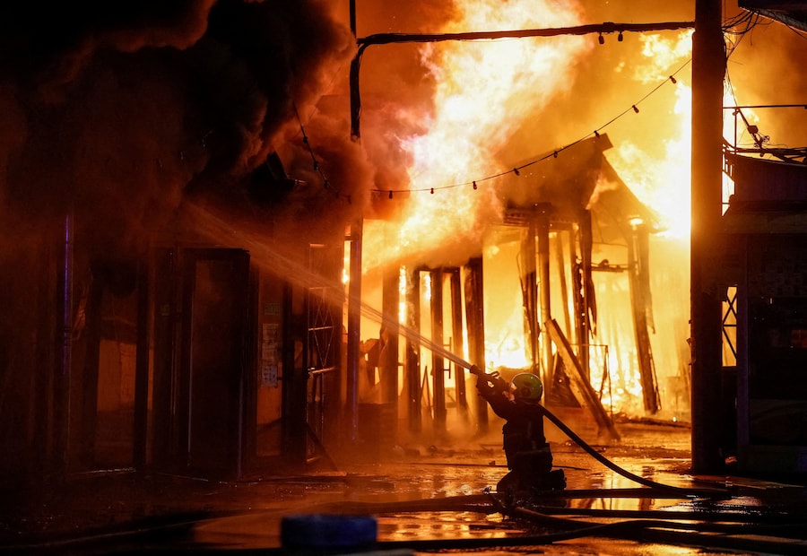 Un vigile del fuoco interviene per spegnere un incendio nel luogo in cui si tiene un mercatino dei libri colpito da un missile russo, nel contesto dell’attacco della Russia all’Ucraina, a Kiev, Ucraina. (REUTERS)