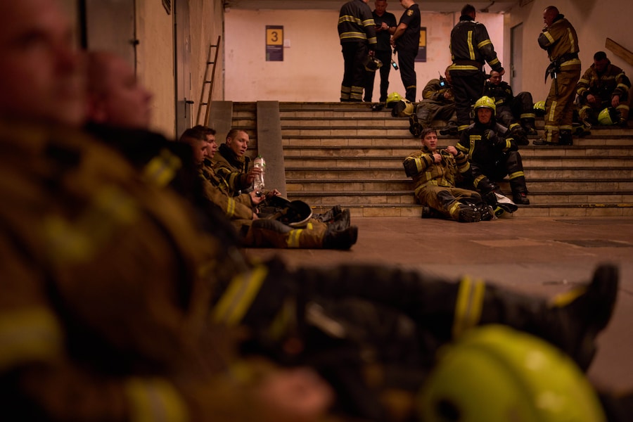 I vigili del fuoco si rifugiano in una stazione della metropolitana dopo l'allarme lanciato dalla sirena, mentre stavano cercando di spegnere un incendio divampato in un mercato librario della città a seguito di un attacco missilistico russo a Kiev, in Ucraina. (APN)