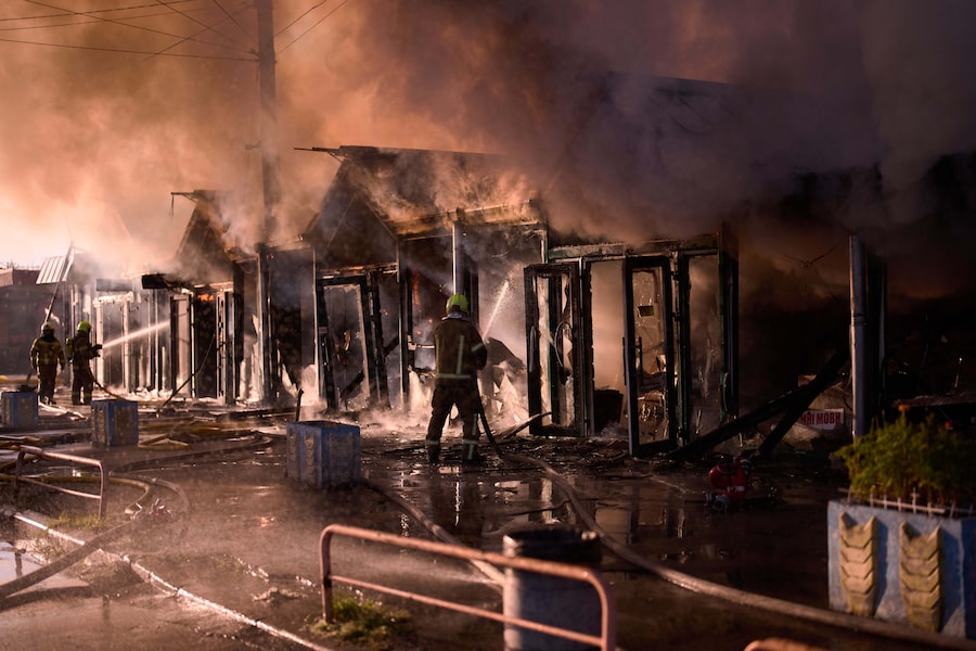 I vigili del fuoco cercano di spegnere un incendio divampato in un mercatino dei libri della città a seguito di un attacco missilistico russo a Kiev, in Ucraina. (APN)