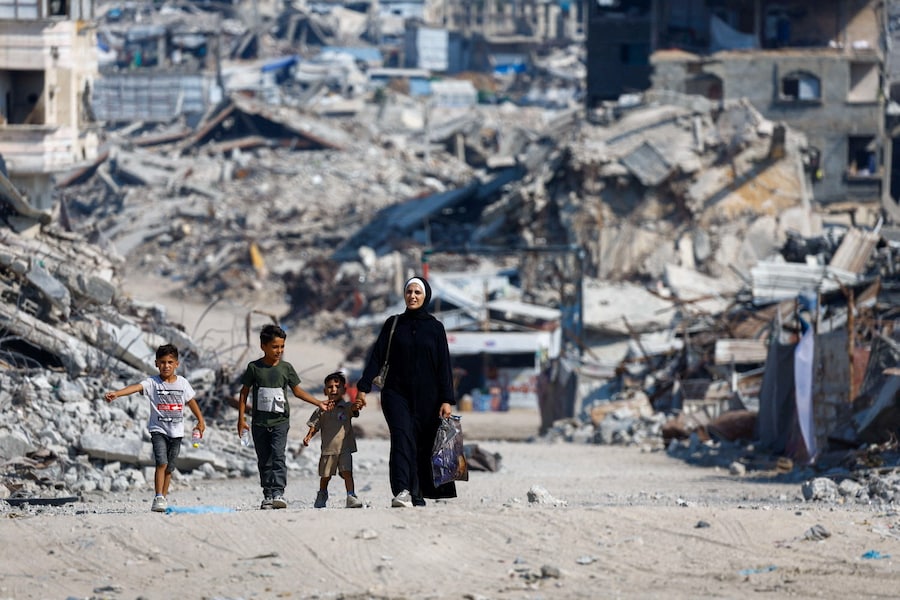 Una donna palestinese con i suoi figli passano accanto alle macerie di edifici residenziali distrutti durante la guerra, nella città di Gaza. (REUTERS/Mahmoud Issa)