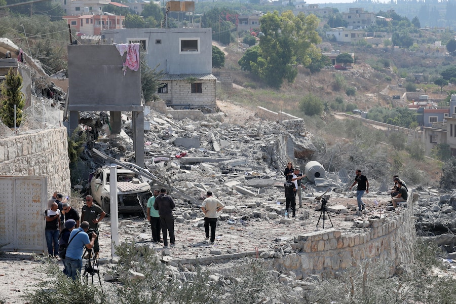 Alcune persone ispezionano un edificio danneggiato dopo un attacco aereo israeliano sul villaggio di Ansar, nel sud del Libano. Secondo l’agenzia di stampa ufficiale libanese (NNA), almeno sette persone sono state uccise e altre due ferite in un attacco aereo israeliano sul villaggio di Ansar. (EPA/Wael Hamzeh)