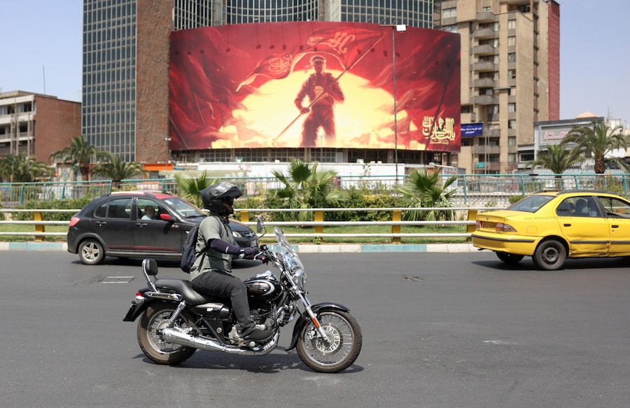 Un iraniano passa in moto davanti a un cartellone politico esposto in piazza Valiasr a Teheran. Il capo dell’esercito iraniano Amir Hatami ha annunciato una taglia di 30.000 dollari USA per l’uccisione o la cattura di personale militare statunitense, offrendo una ricompensa doppia alle donne iraniane che compiano tale azione, secondo quanto riportato dai media statali iraniani. (EPA/Abedin Taherkenareh)