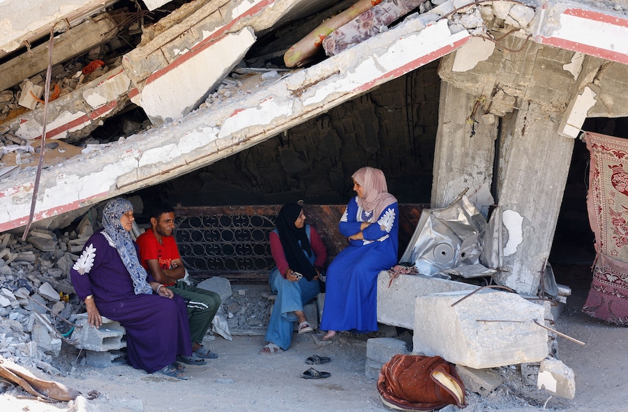 Alcune persone sono sedute in un luogo distrutto durante l’offensiva israeliana, a Beit Lahiya, nella parte settentrionale della Striscia di Gaza. (REUTERS/Mahmoud Issa)
